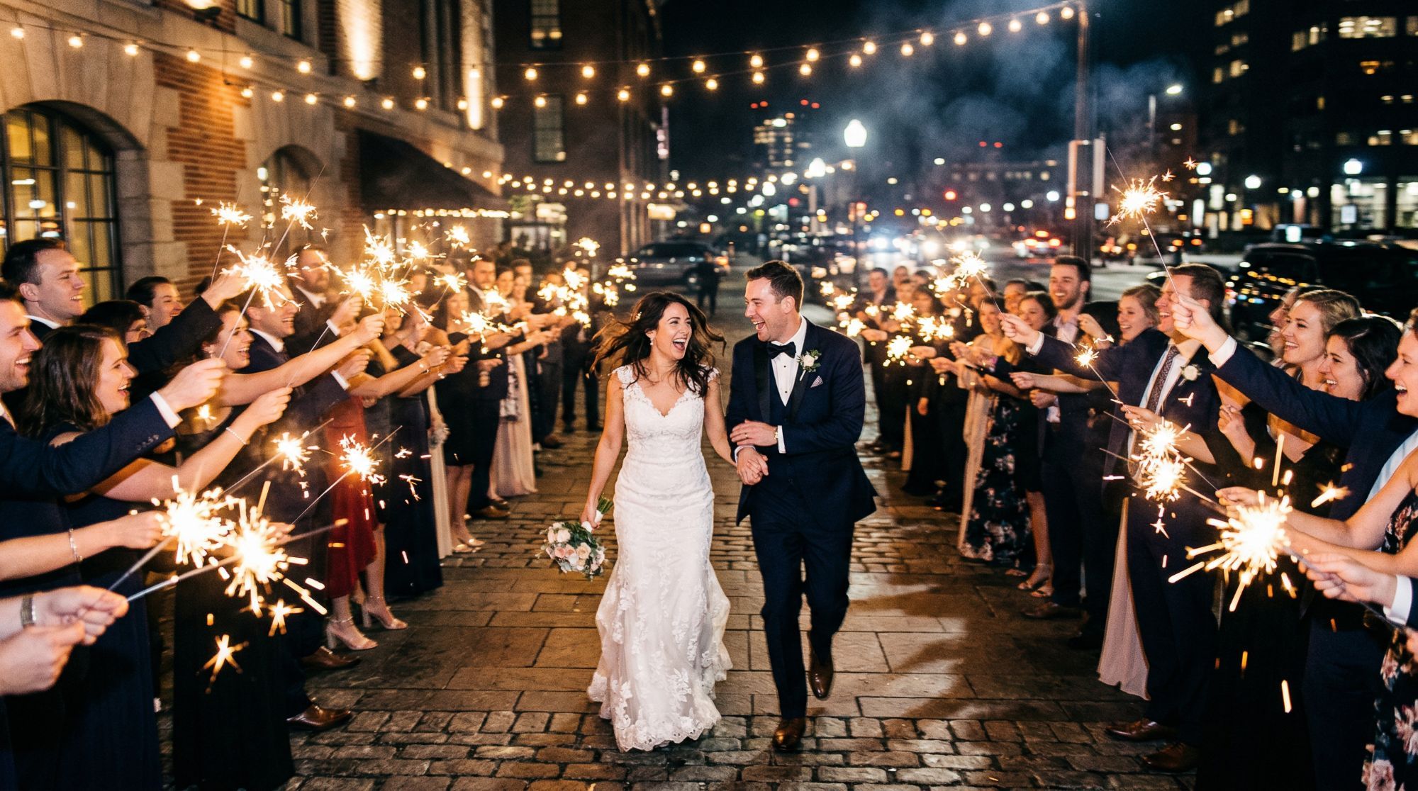 Couple walking through a sparkler send-off on a city street